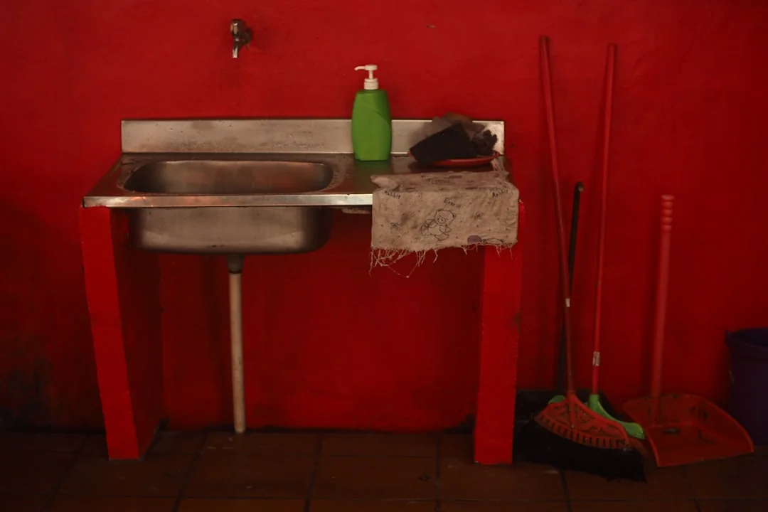 Anonymous person in yellow rubber gloves using simple sponge for cleaning mirror in bathroom